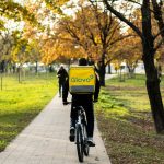A Glovo worker cycling through a park.